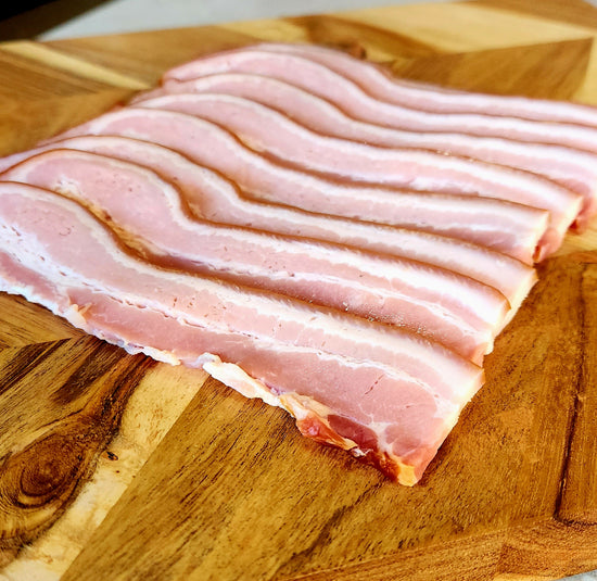 Raw bacon strips on a wooden cutting board