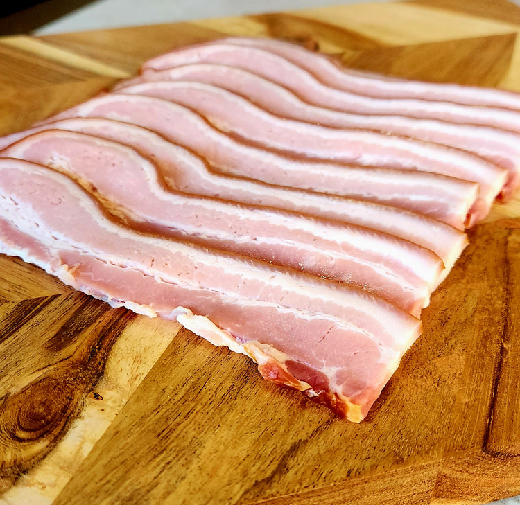 Raw bacon strips on a wooden cutting board
