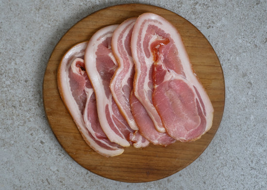 Uncooked bacon slices on a wooden board.